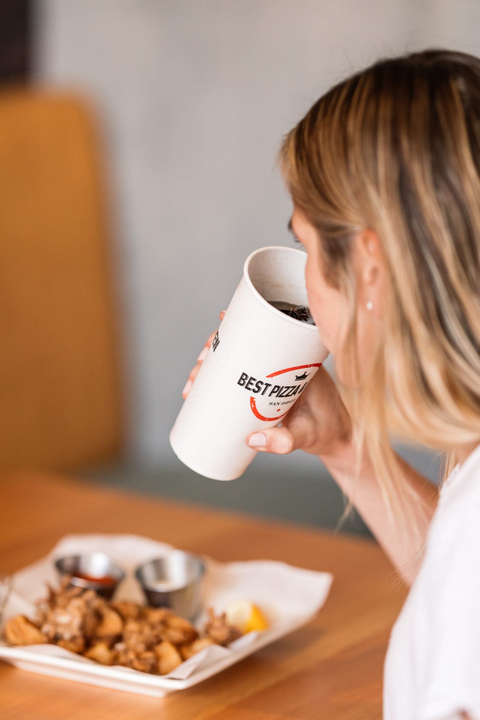 A guest drinking from a Best Pizza & Brew cup