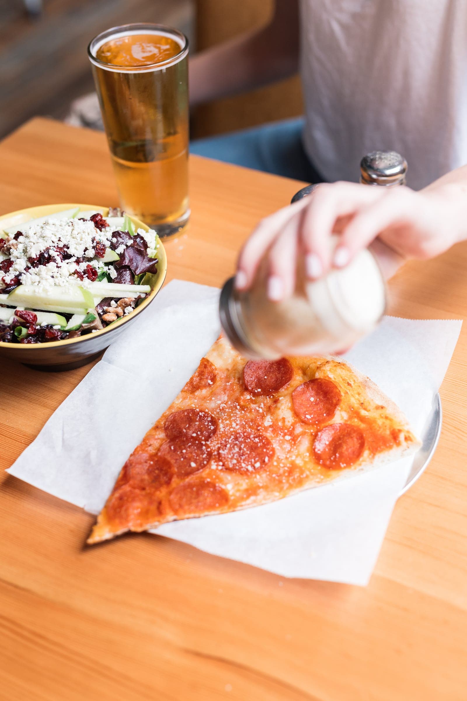 A hand lifting a pepperoni slice from the tray