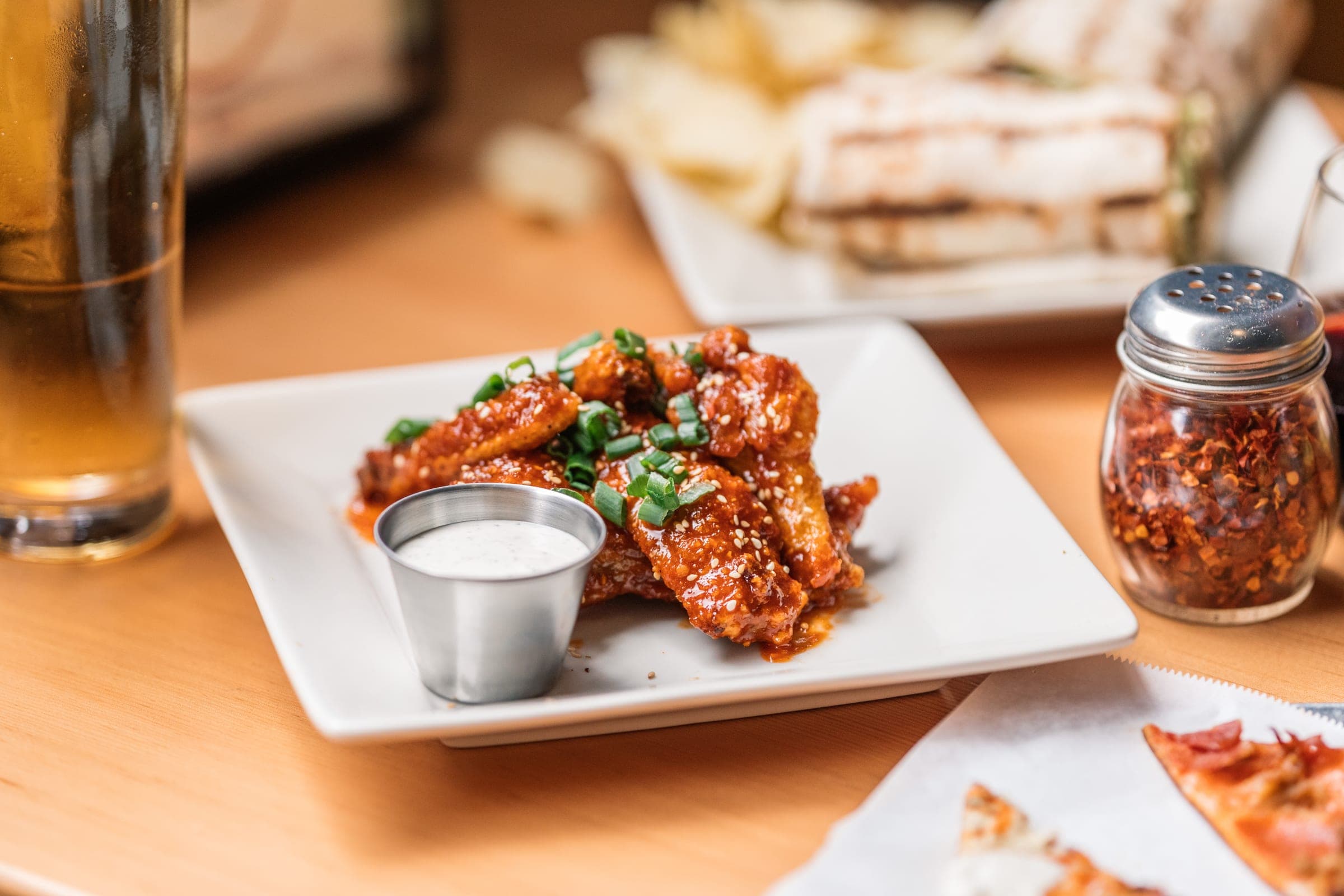 A plate of glazed wings with a ramekin of ranch dressing
