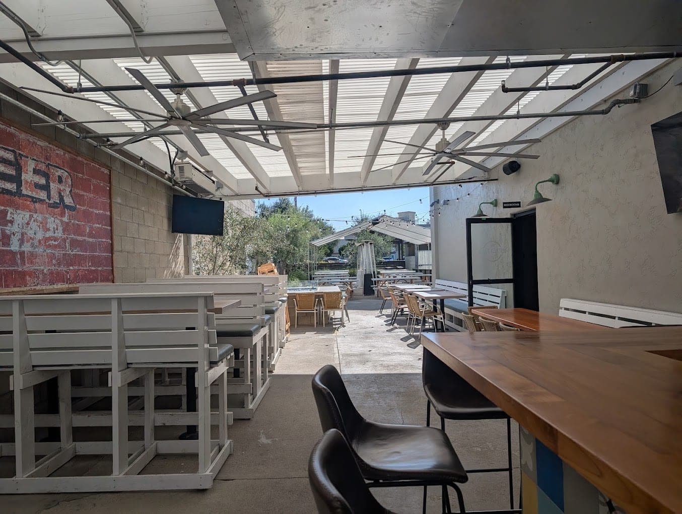 The covered side patio at Best Pizza & Brew Escondido, with a long wooden communal table