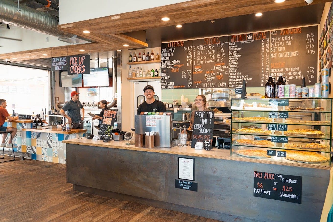 The order counter at Best Pizza & Brew Escondido, with chalkboard menus above and staff at the till