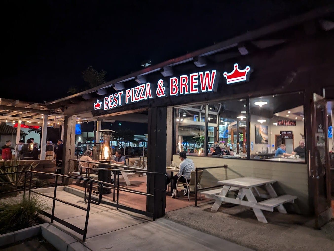 Best Pizza & Brew Mira Mesa lit up at night, with its illuminated sign above patio picnic tables