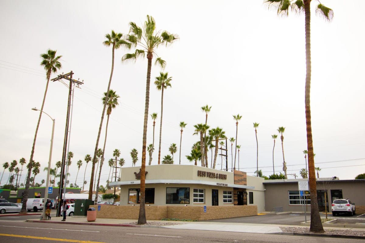 Best Pizza & Brew Oceanside on South Coast Highway, with tall palm trees lining the street