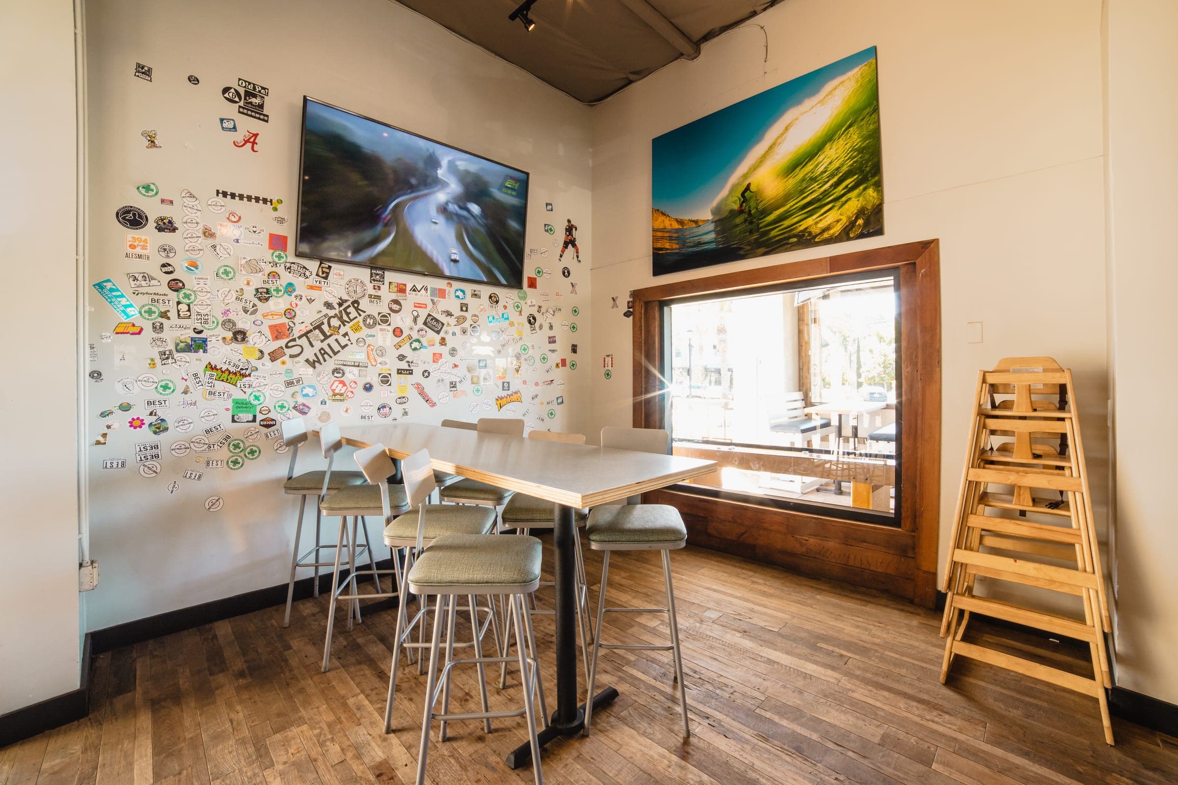 Communal seating at Vista beneath surf photography and a sticker wall