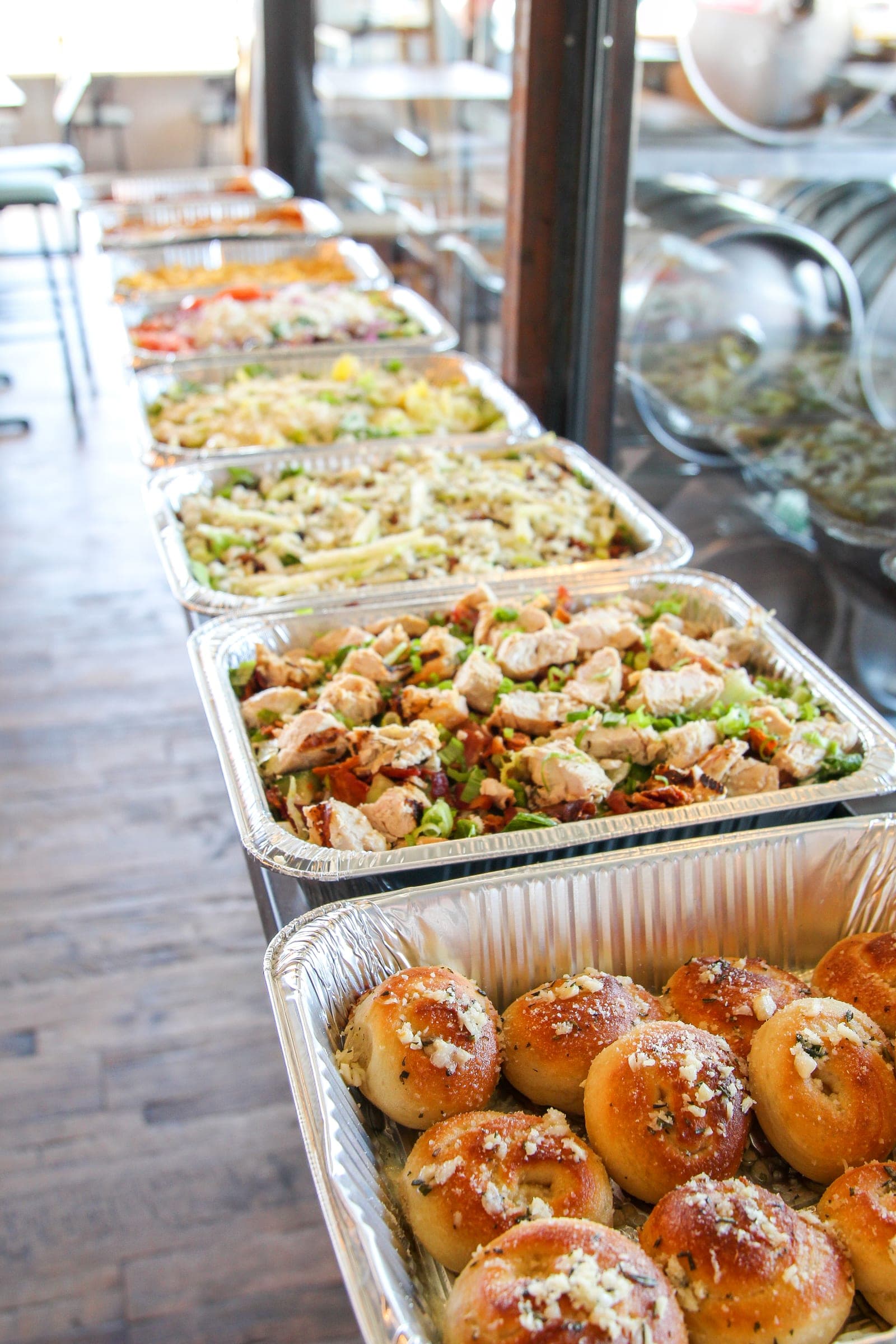 Foil catering trays of pan salads laid out for a large order